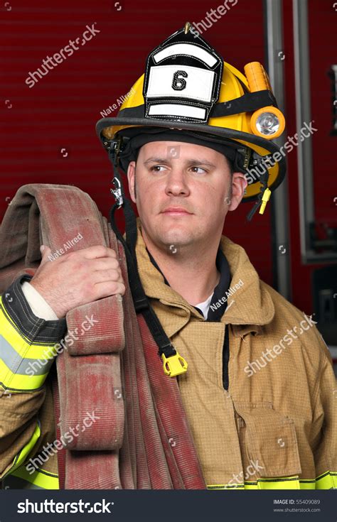 Handsome Young Fireman Holding Fire Hose In Uniform In Front Of