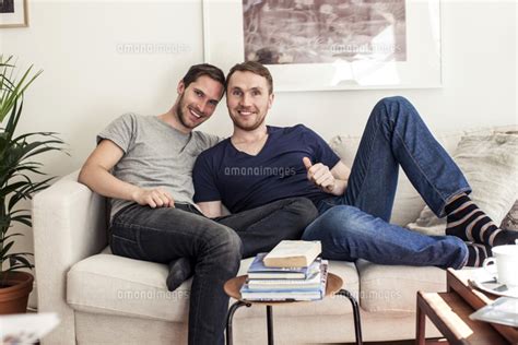 Portrait Of Homosexual Couple Sitting Together On Sofa At Ho