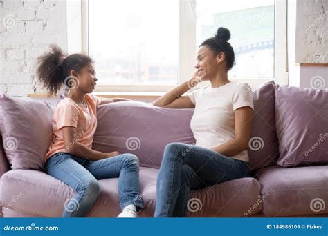 African Mother And Daughter Talking Sitting On Couch At Home Stock