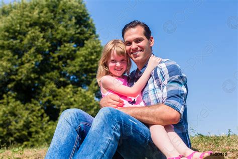 Girl On Dads Lap Sitting On Meadow Or In Field Stock Photo Crushpixel