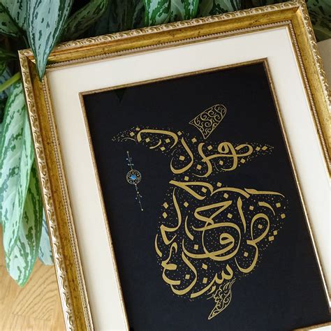 An Arabic Calligraphy Is Displayed In A Gold Frame On Top Of A Wooden Table