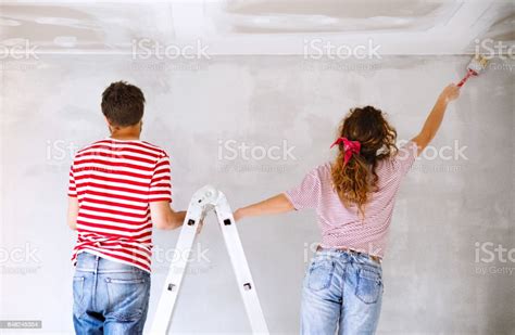 Young Couple Painting Walls In Their New House Stock Photo Download