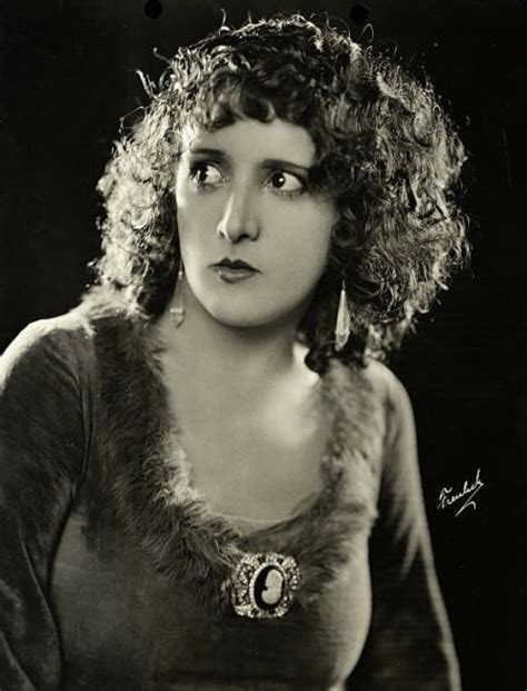 an old black and white photo of a woman with curly hair wearing a fur collar