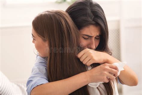 Girl Crying Hugging Her Compassionate Friend Sitting On Couch Indoor