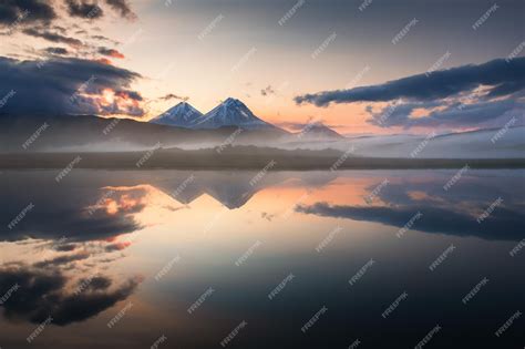Premium Photo Volcanoes And Their Reflections In The Lake At Sunrise