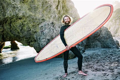 Caucasian Man Holding Surfboard At Beach Stock Photo Dissolve