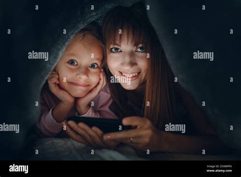 Madre Adulta Joven Y Hija Pequeña Usando El Teléfono Móvil Juntos Bajo