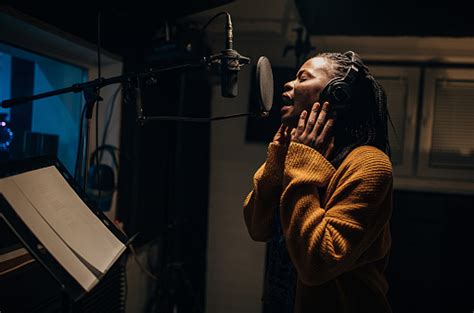 Black Female Singer Singing Into Microphone In Recording Studio Stock