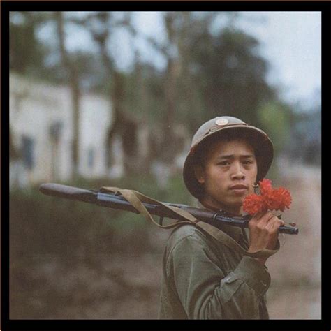 A Vietnamese Soldier Holding A Flower With His Rifle During The March