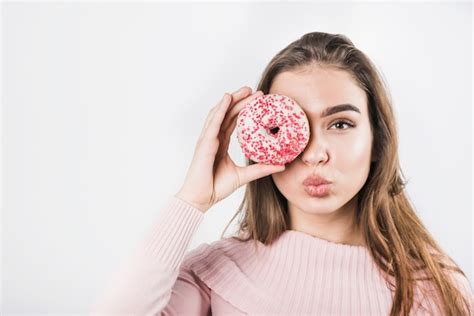 Free Photo Young Woman Pouting Her Lips Covering Her Eyes With Donut