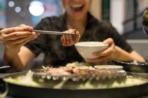 The food is pretty standard korean bbq fare. Woman's hand use chopsticks hold korean pork grilled | Premium Photo