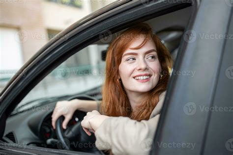 Joyful Redhead Woman Inside Of Car Looking Back From Driver Seat While