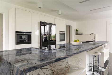 A Modern Kitchen With Marble Counter Tops And White Cabinets Along