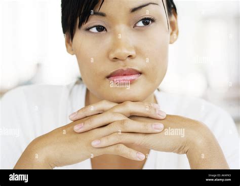 Young Woman With Hands Clasped Under Chin Looking Away Stock Photo Alamy