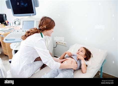 High Angle Of Friendly Female Doctor Examining Little Girls Abdomen