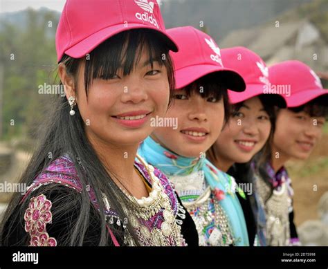 Four Vietnamese Hmong hill-tribe teen girls sit in a row, wear modern ...