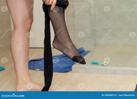 A Close Up Portrait Of A Woman Sensually Pulling Up Sheer Black Nylon Pantyhose With A