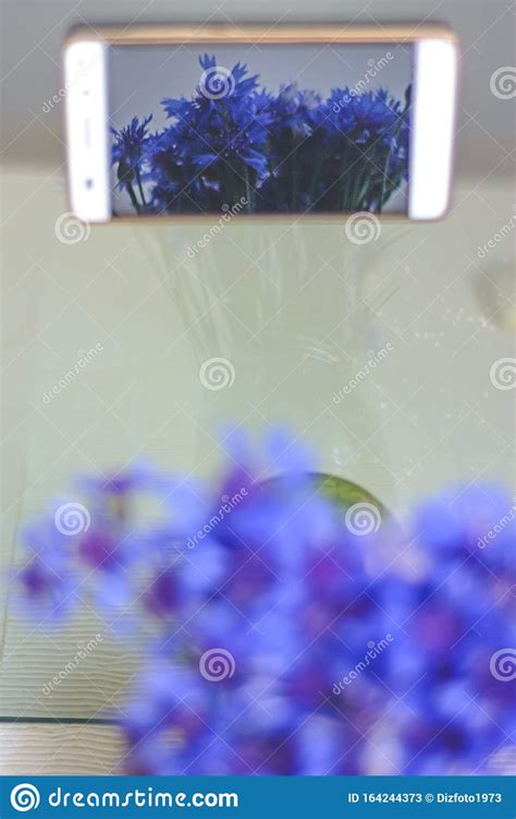 A Bouquet Of Blue Flowers Of Cornflowers In The Reflection Of A Mobile