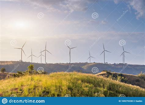 Wind Turbines Farm On Mountanis Landscape Against Blue Sky With Clouds