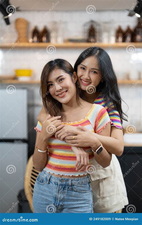 Smiling Young Asian Lesbian Couple Standing Affectionately Together At