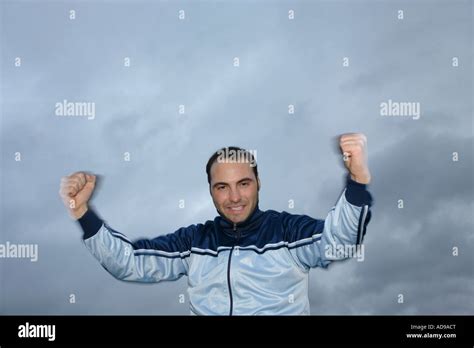 Young Man In A Sweat Suit Jacket Cheering In Front Of Dark Clouds Stock