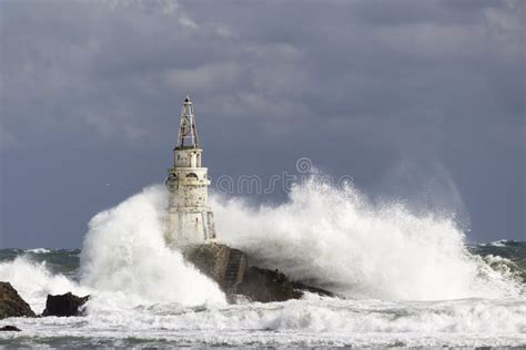 Lighthouse Over Waves In A Stormy Sea In The Sunlight Stock Photo