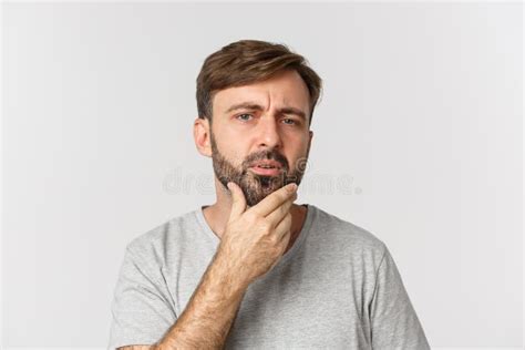 Close Up Of Confused Man Touching His Beard And Looking At Himself