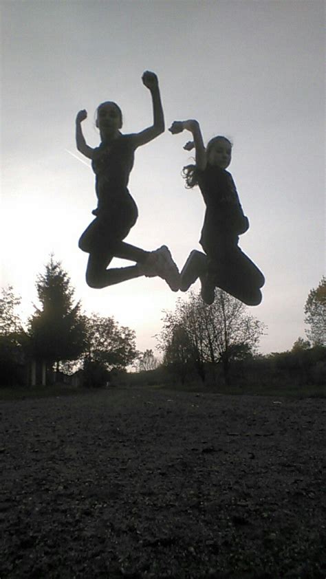 Two People Jumping In The Air With Their Arms Up