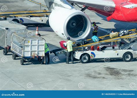 Man Puts Luggage On The Conveyor Belt On The Plane Editorial Image