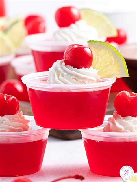 Dirty Shirley Temple Jello Shot With Whipped Cream Cherry And Lime Garnish
