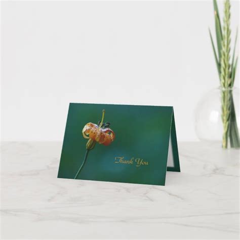 A Card With An Orange Flower On It Sitting Next To A Vase Filled With