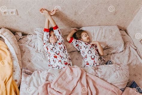 Duas Irmãs Mais Nova Vestidas Nos Pijamas Que Dormem Na Cama No Quarto Foto De Stock Imagem De