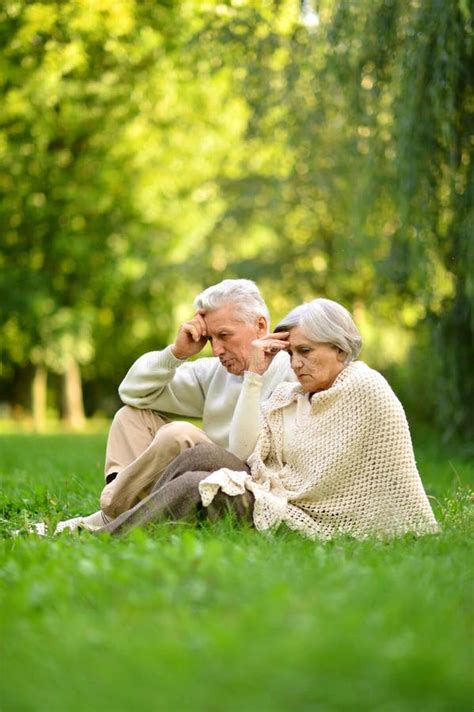 Portrait Of Loving Elderly Couple Sitting On Green Grass In The Summer