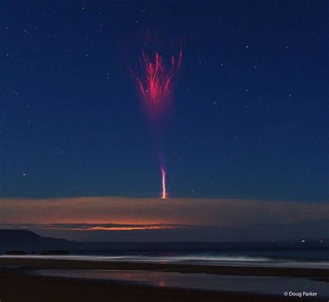 Fireworks Are Lit Up In The Night Sky Over Water And Beach At Low Tide