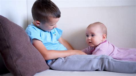 Smiling Brother Playing With His Little Sister On Sofa Stock Video