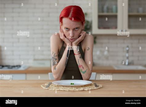 Skinny Woman Suffering From Anorexia Sitting In The Kitchen Stock Photo
