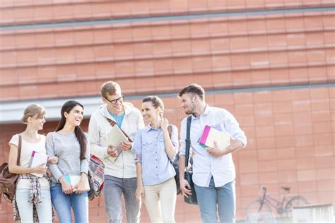 Happy Friends With Books Talking While Walking In University Campus