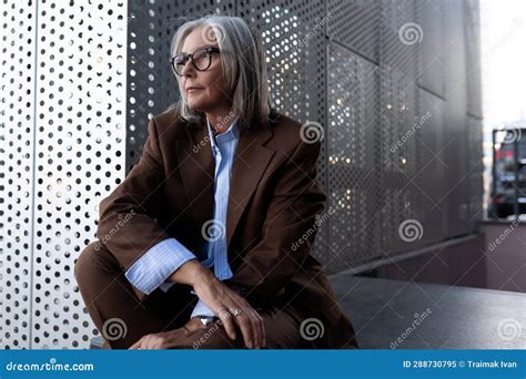 well groomed healthy slender gray haired mature business lady dressed in a stylish brown jacket