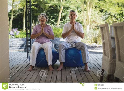 Full Length Of Senior Couple Meditating Together While Sitting At Porch Stock Image Image Of