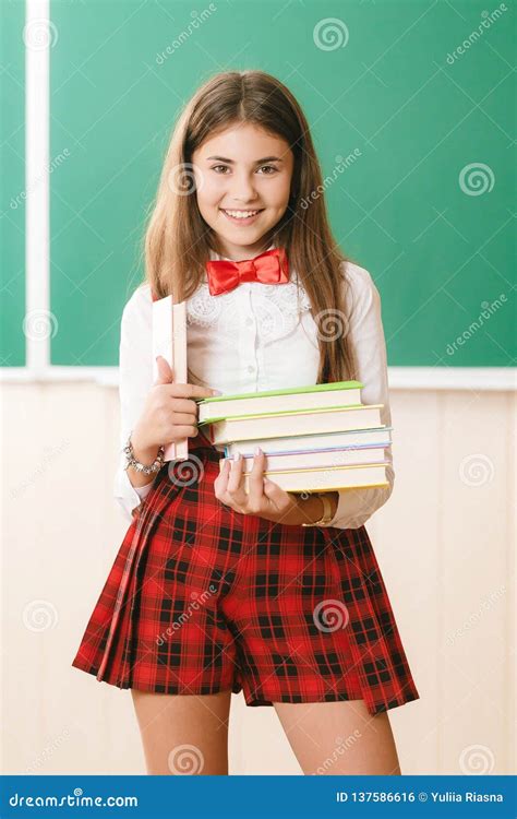Beautiful Schoolgirl In Red School Uniform Standing With Books In Front