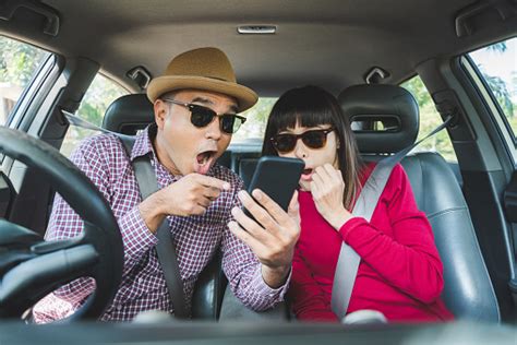 Çift asyalı adam ve kadın arabada oturan ve smartphone bakıyor seyahat konsepti stok fotoğraflar