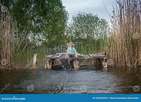 Niña Alegre Salpicando Con Piernas En El Agua En El Muelle En La Infancia Feliz Del Lago Foto de