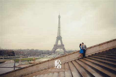 A Couple Standing On The Steps In Front Of The Eiffel Tower