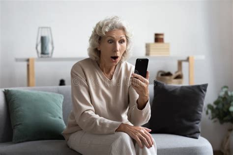 Excited Mature Granny Surprised By Unbelievable Mobile News Stock