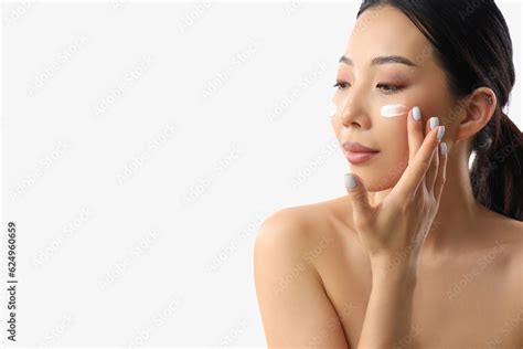 Beautiful Asian Woman Applying Facial Cream Against White Background Stock Photo Adobe Stock