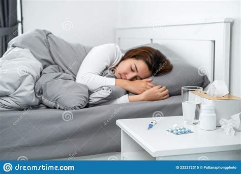 asian woman feeling sick and sleeping in blanket on the bed after using thermometer to checking