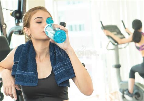 Sport Women Drinking Water And Eat Apple While Exercising In Fitness