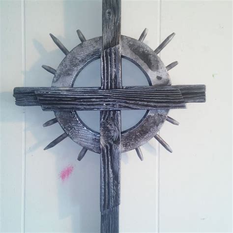 A Wooden Cross Mounted To The Side Of A Wall With Spikes On Its Sides
