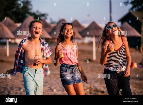 Happy Children Having Fun While Walking Along A Sandy Beach Summer And