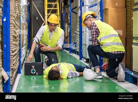 Warehouse Worker Do First Aid To His Colleague Lying Down On Warehouse Floor After Accident